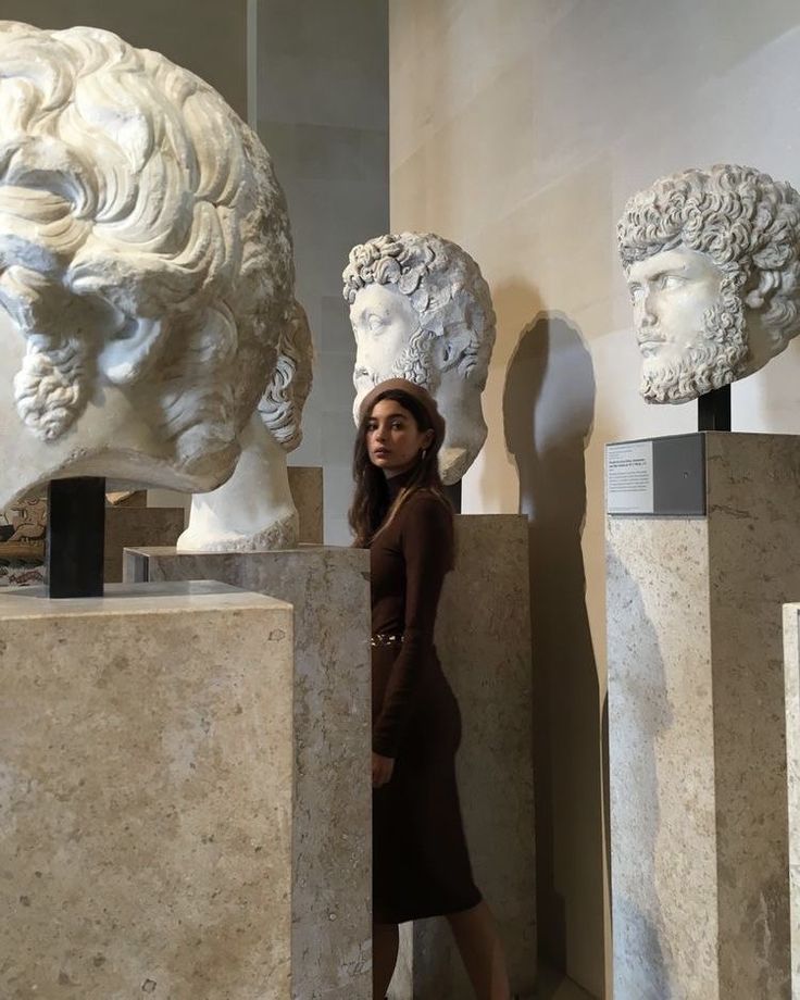 a woman standing in front of some marble busturines on display at a museum