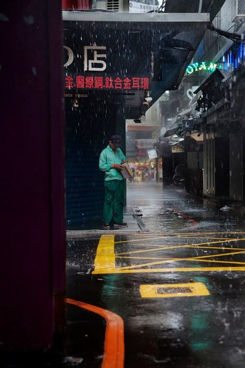 a man is standing in the rain with an umbrella