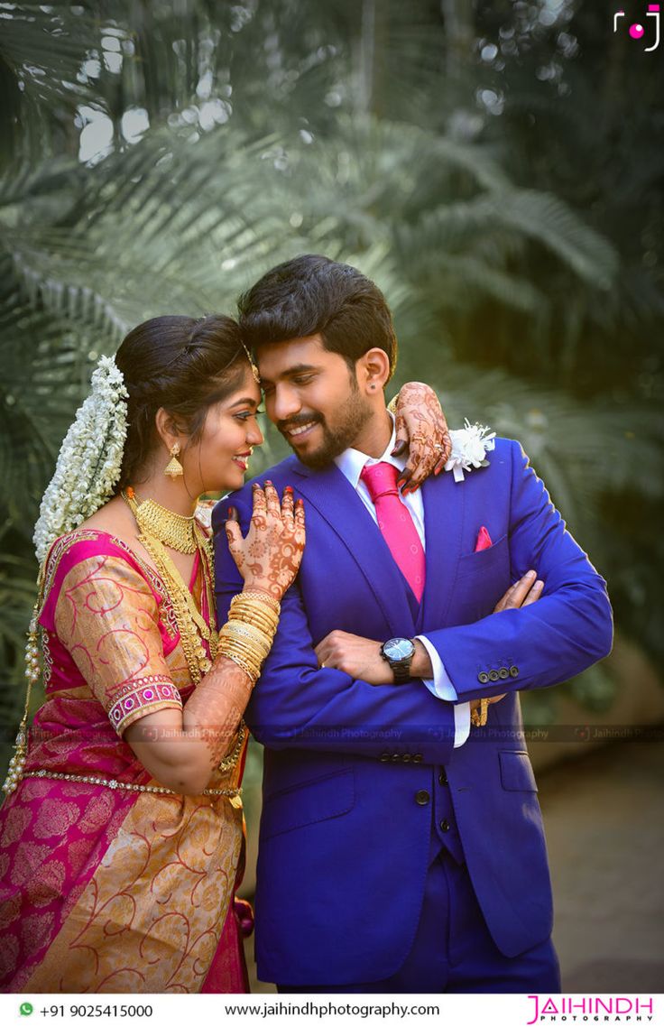 a man in a blue suit and tie hugging a woman wearing a pink sari