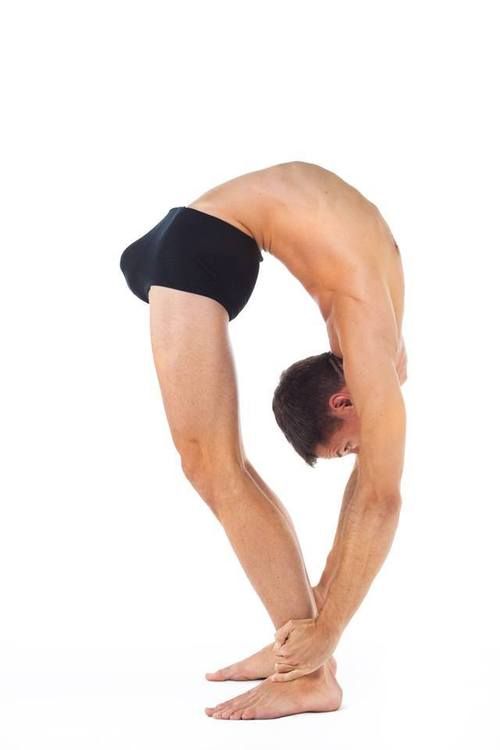 a man in black shorts and no shirt doing a handstand on his knees