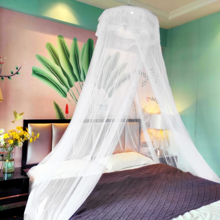 a bed with a white canopy over it in front of a painting on the wall