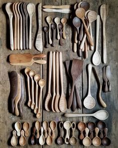 many wooden spoons are lined up on a table with different shapes and sizes in them