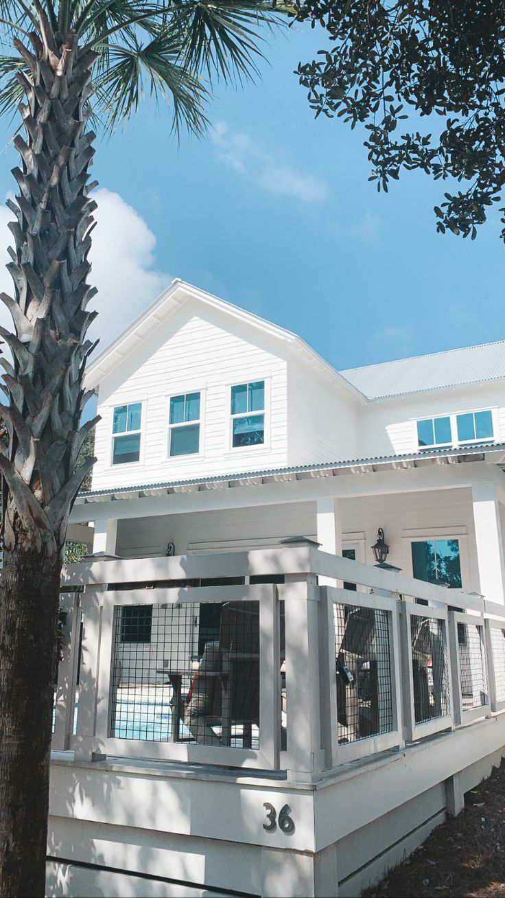 a large white house sitting next to a palm tree