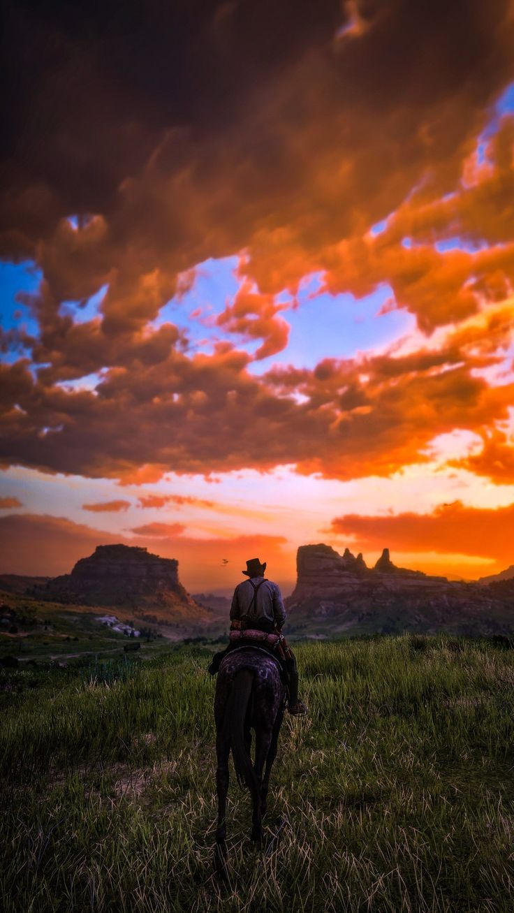 a man riding on the back of a brown horse under a colorful sky with clouds