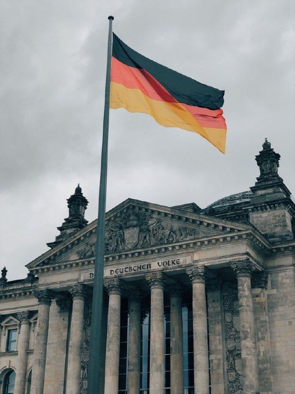 the german flag is flying in front of an old building with columns and pillars on it