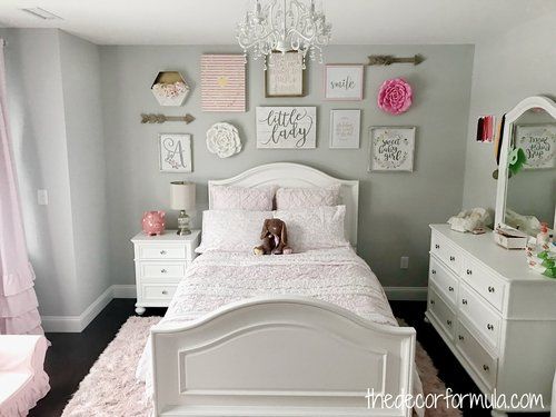 a white bed sitting in a bedroom next to a dresser and window with pink curtains