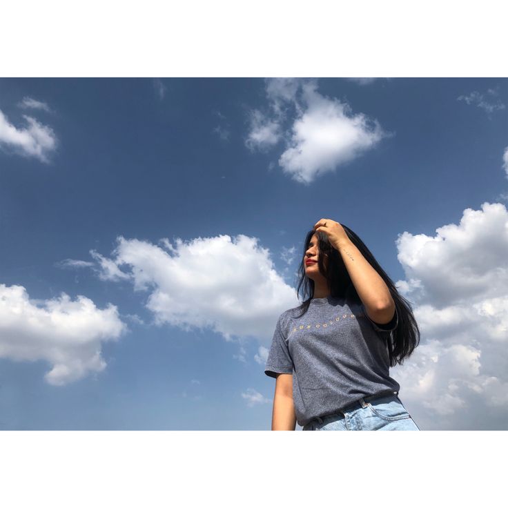 a woman standing under a cloudy blue sky