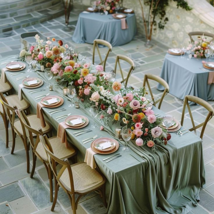 a long table is set with flowers and place settings for an outdoor dinner party or wedding reception