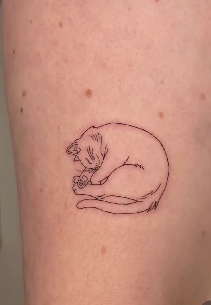 a small tattoo of a cat on the back of a woman's thigh,