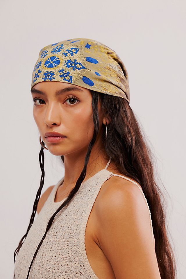 a young woman with long hair wearing a headband and looking at the camera while standing in front of a white wall