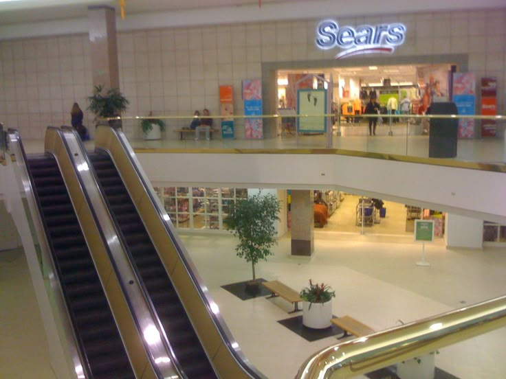 an escalator in a shopping mall with people walking down the escalators