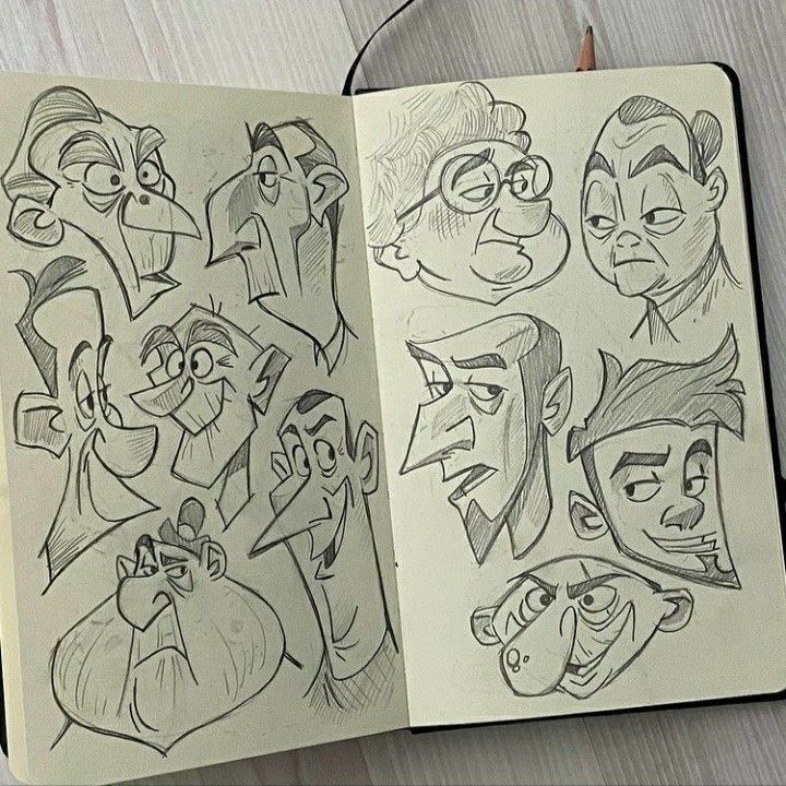 an open notebook with drawings of cartoon faces and noses on the pages, along with a pen