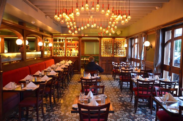 a restaurant with many tables and chairs in front of large windows, chandeliers hanging from the ceiling