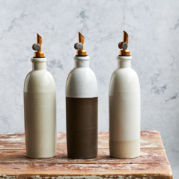 three white and brown bottles sitting on top of a wooden table