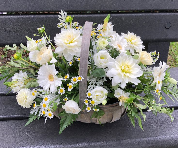 a basket filled with white flowers sitting on top of a bench