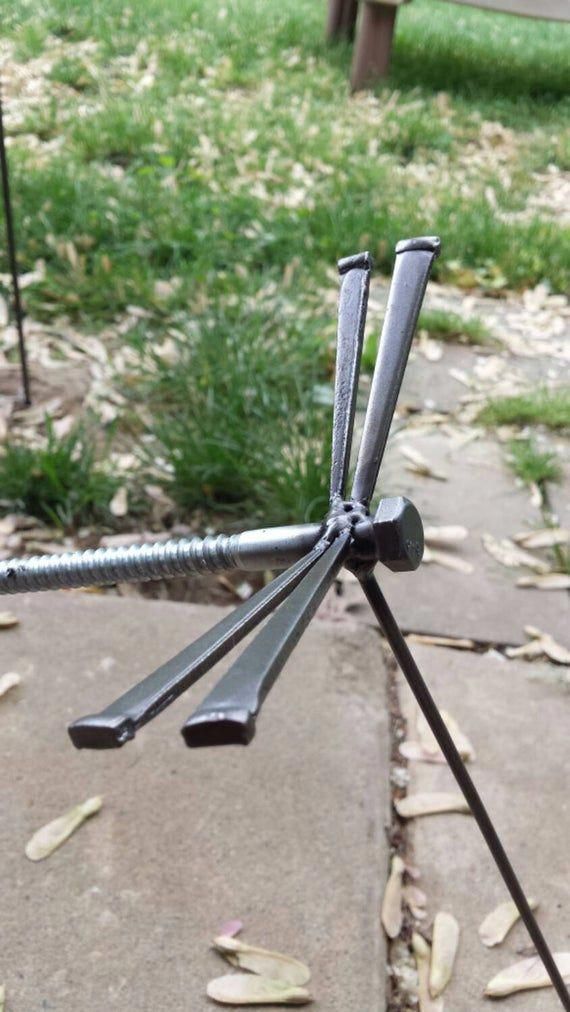 a metal object sitting on top of a cement ground next to grass and trees in the background