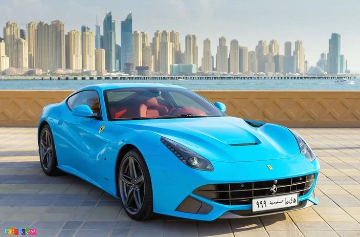 a blue sports car parked in front of a city skyline