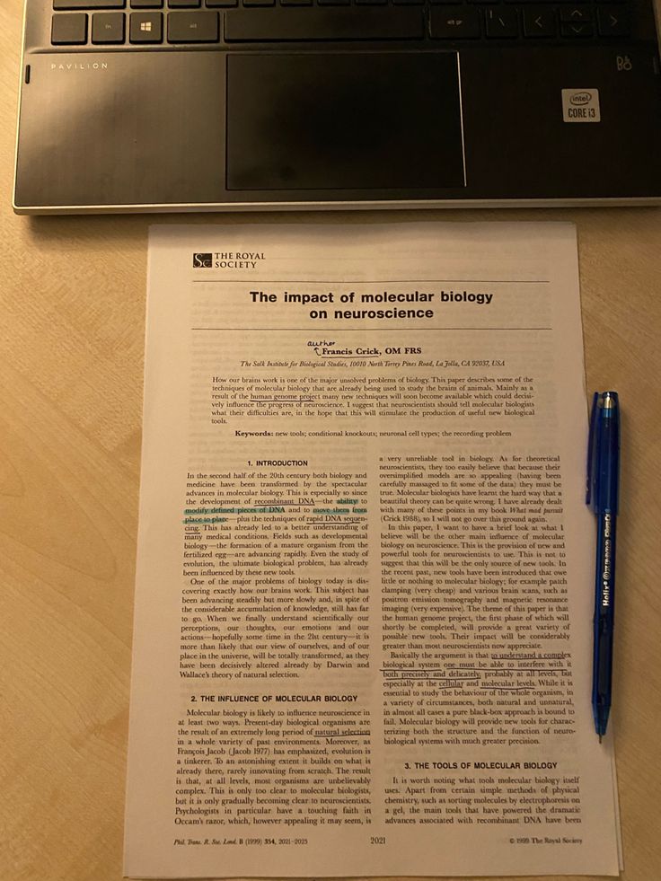 an open laptop computer sitting on top of a wooden table next to a paper and pen