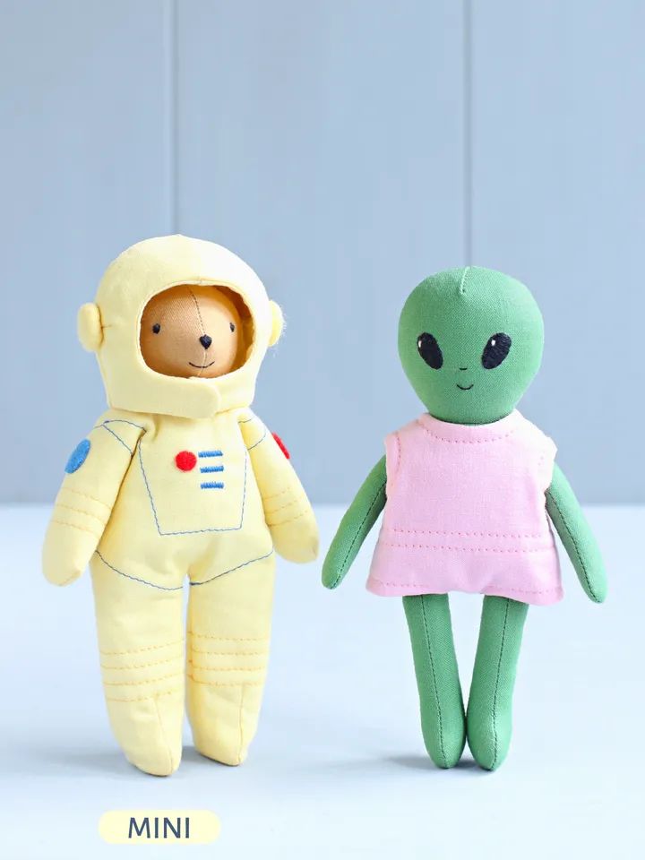 two small stuffed animals in space suits, one wearing an astronaut's suit and the other as a baby