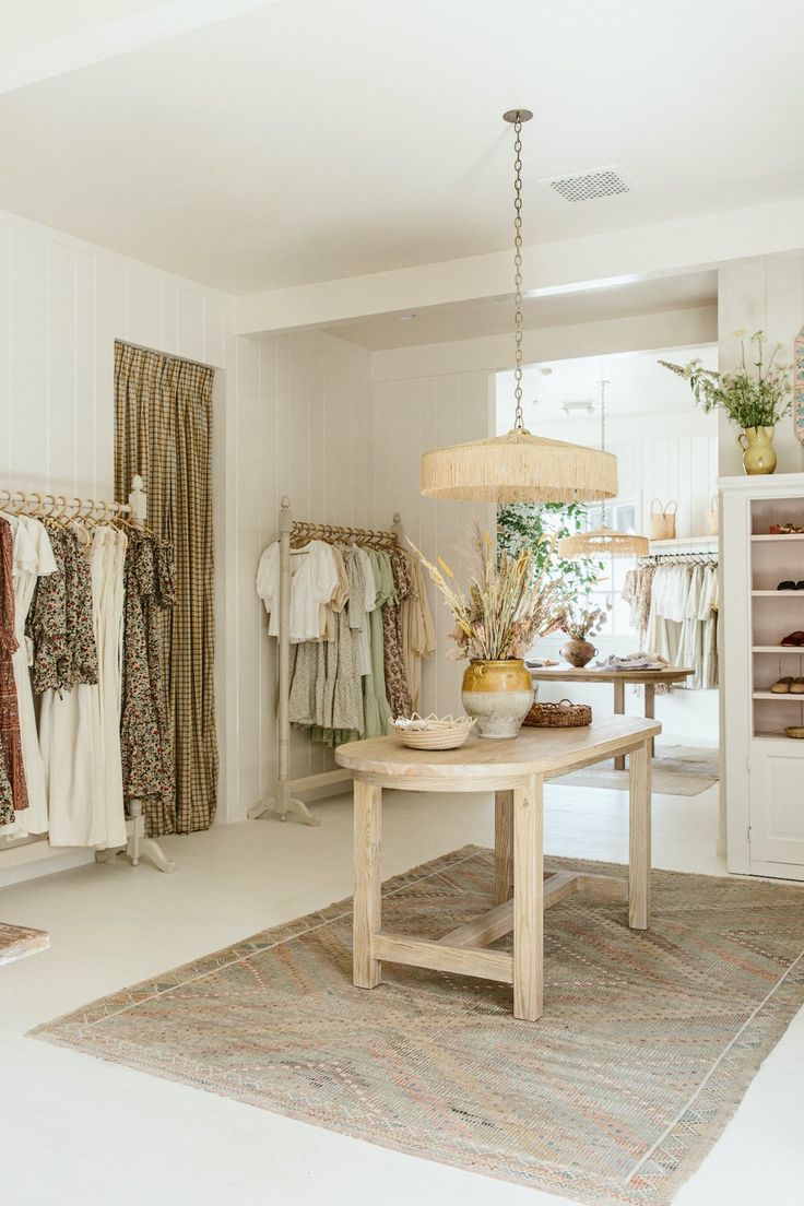 a room filled with lots of clothes on hangers next to a table and lamp