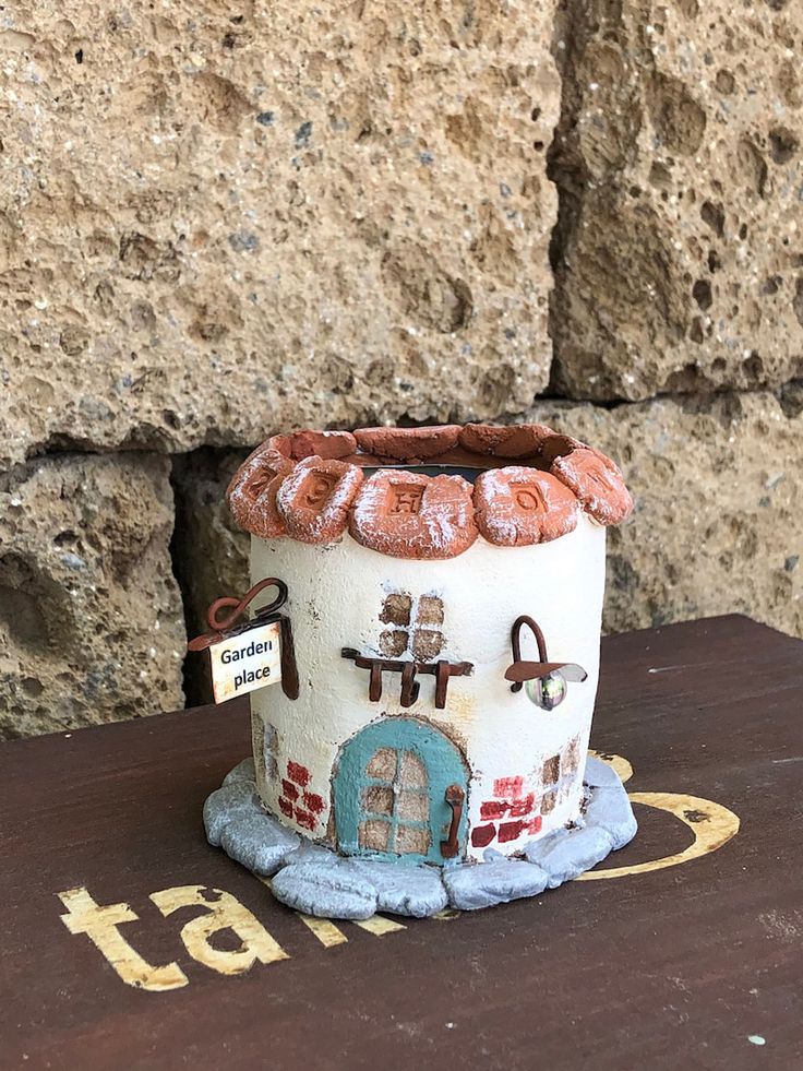 a small ceramic pot sitting on top of a wooden table next to a stone wall