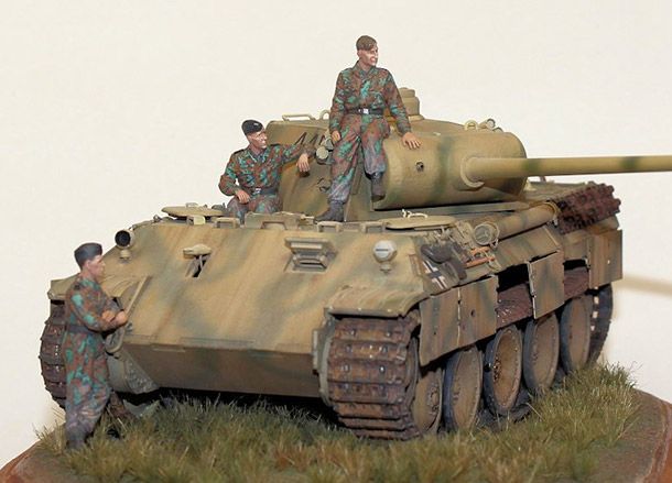 two men standing on top of a tank with another man in the back ground next to it