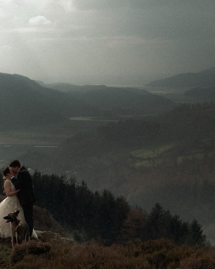 a bride and groom standing on top of a hill