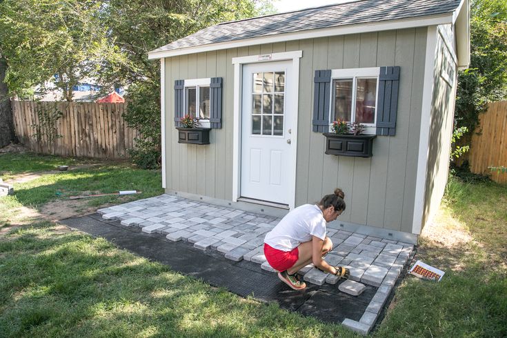 a woman kneeling down in front of a shed