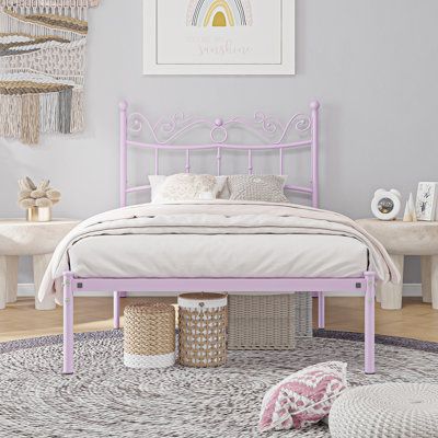 a pink metal bed frame in a white bedroom with wicker baskets on the floor