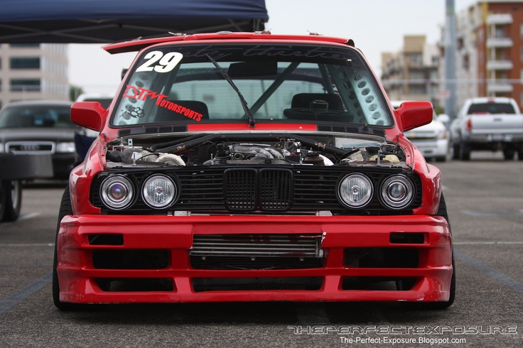 the front end of a red car parked in a parking lot