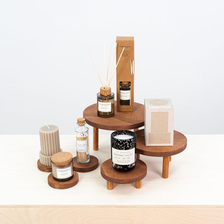 three small wooden tables with candles and bottles on them sitting on top of a white surface