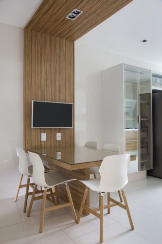 a dining room table with white chairs and a flat screen tv mounted on the wall