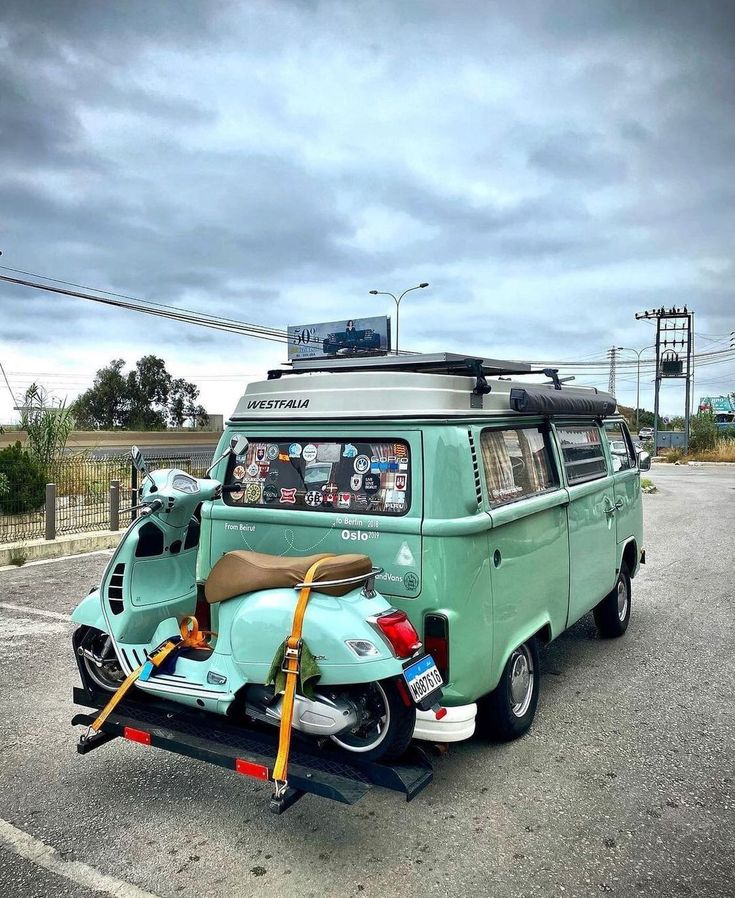 an old vw van is parked in a parking lot with a motor scooter attached to it