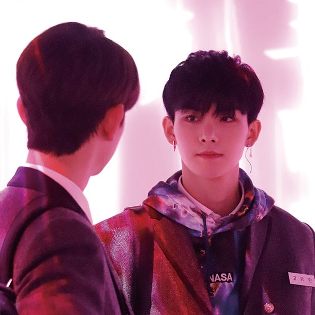 two young men standing next to each other in front of a wall with light coming through it