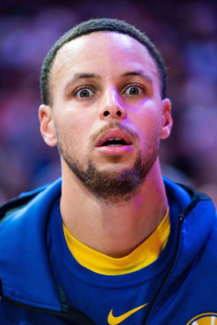 a close up of a basketball player wearing a blue jacket and yellow shirt with his eyes wide open