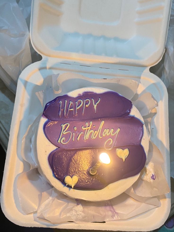 a birthday cake in a white box with purple frosting