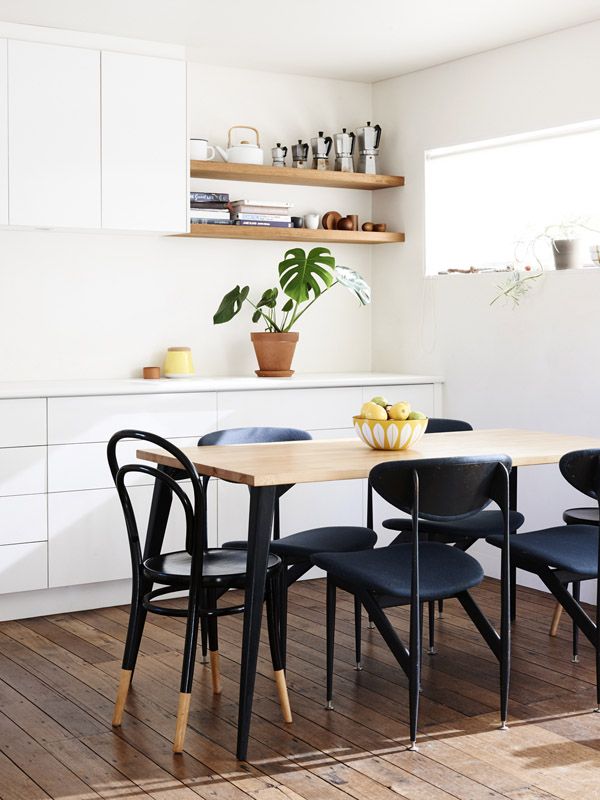 a kitchen table with four chairs and a bowl of fruit on the counter next to it