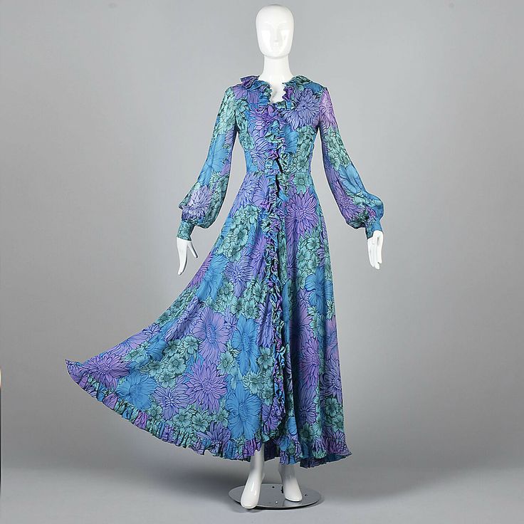 Small 1970s La Mendola Flowy Silk Maxi Dress Formal Evening Gown Signature Print Description: This dress is gorgeous! Textile is silk printed in a large floral using shades of blue with La Mendola signatures throughout. Zips up the front, zipper is hidden in ruffles that trim the collar and hem as well. Fitted bodice has a v-neck. Long, full, poet sleeves with fitted button cuffs. The skirt is full and flowy with a curved hem in the center front. There are a couple of small, subtle spots on the Blue Floor-length Vintage Gown, Blue Vintage Floor-length Gown, Vintage Long Dresses For Formal Occasions, Vintage Blue Maxi Dress For Formal Occasions, Vintage Floor-length Maxi Dress For Events, Vintage Floor-length Maxi Dress For Vintage Events, 1970s Style Maxi Dress With Vintage Print, 1970s Maxi Dress With Vintage Print, Vintage Long Evening Dress