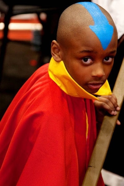 a young boy with blue and yellow painted on his head is standing next to a ladder