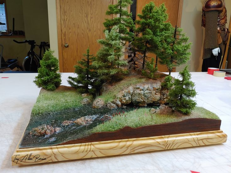 a small model of a river running through a forest with rocks and trees on it