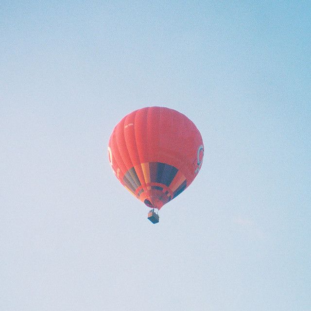 a red hot air balloon flying in the sky with no clouds on it's side