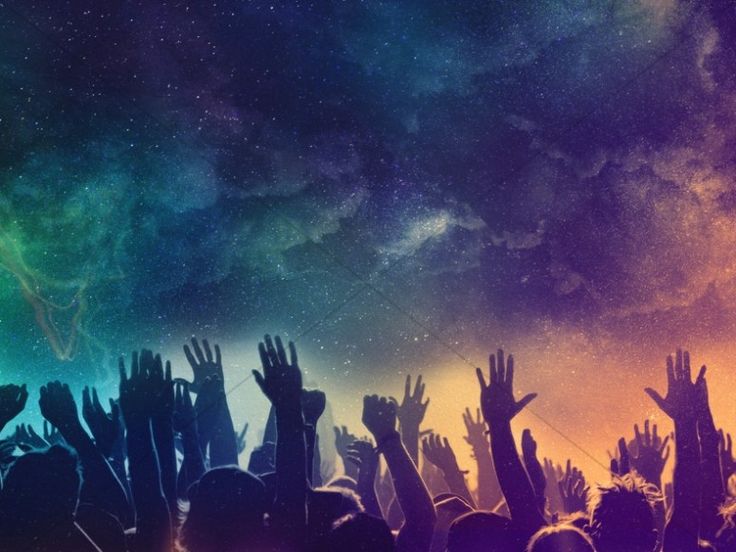 a group of people with their hands up in the air at a concert under a night sky filled with stars