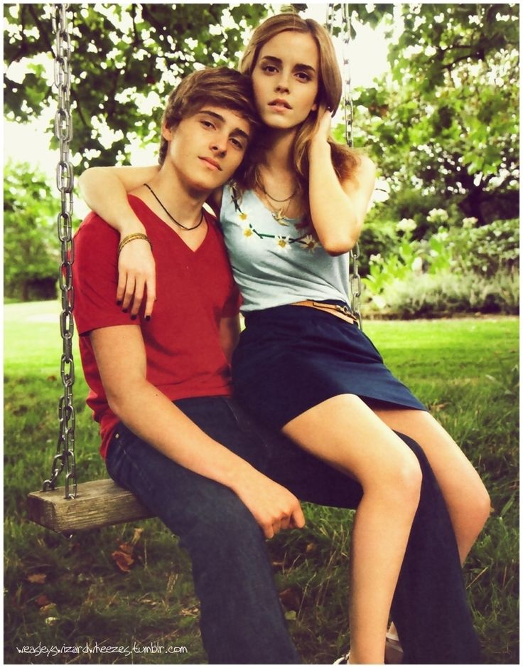 two people sitting on a swing in the grass