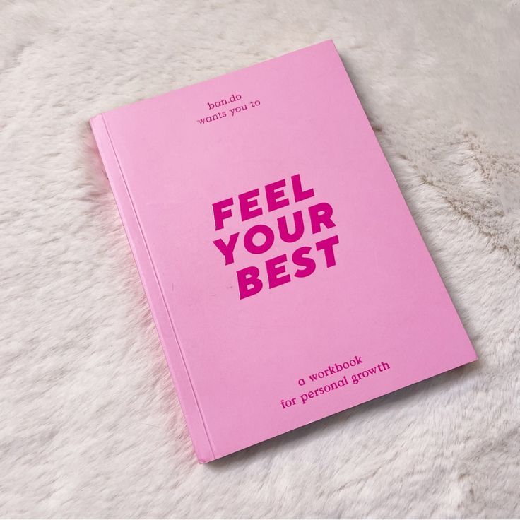 a pink book with the words feel your best on it sitting on a fluffy white surface