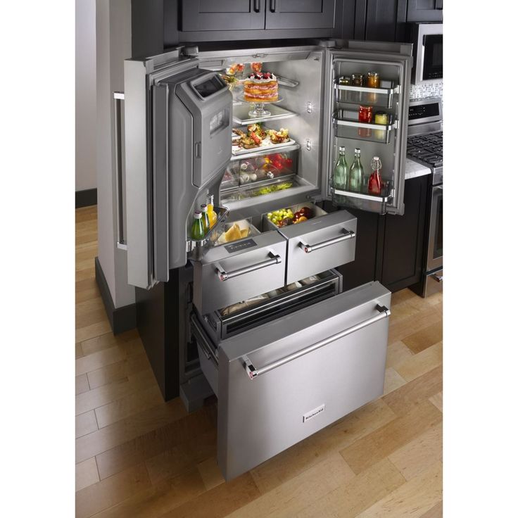 an open refrigerator and freezer combo in a kitchen with wood floors, black cabinets and stainless steel appliances