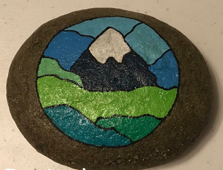 a painted rock with a mountain scene on it