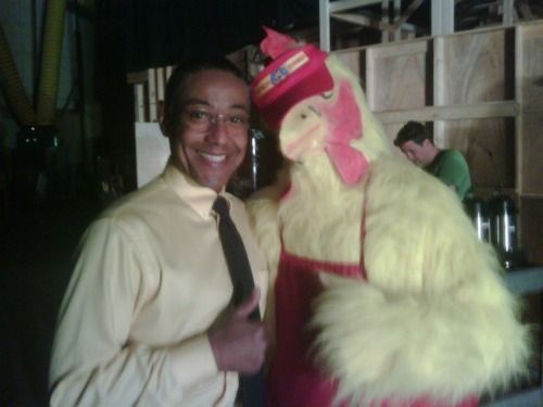 a man standing next to a large chicken mascot wearing a tie and dress up shirt