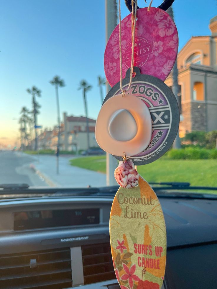 an air freshener hanging from the dashboard of a car with palm trees in the background