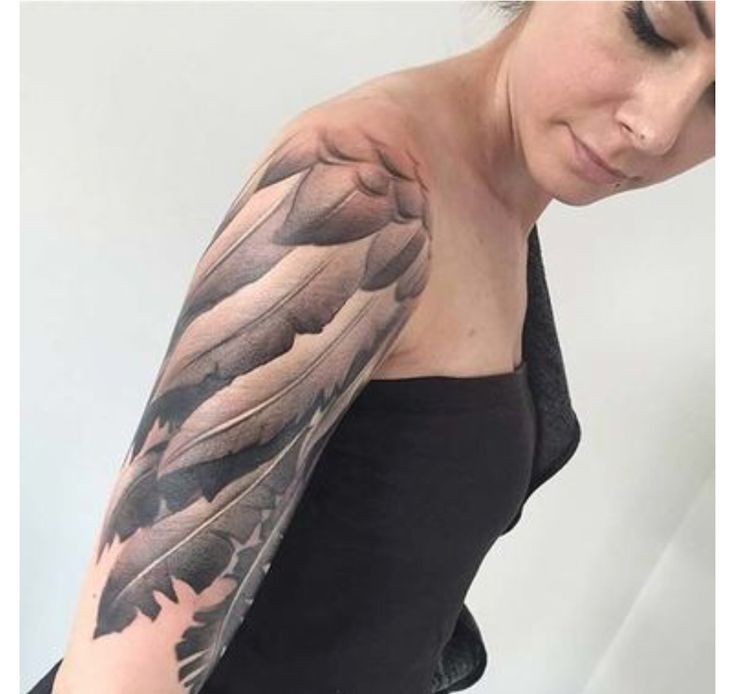 a woman with a black and grey feather tattoo on her arm