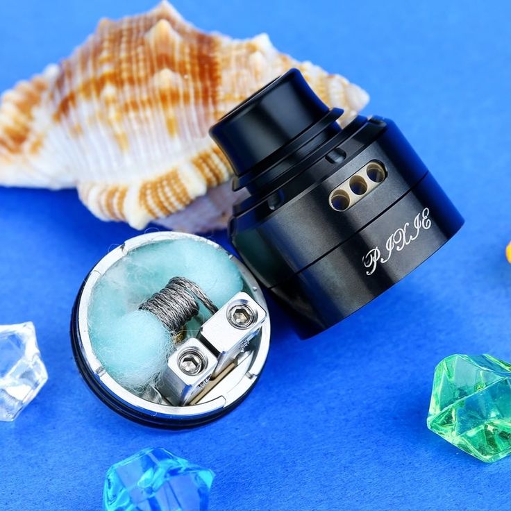 an electronic device sitting on top of a blue surface next to some crystal stones and shells